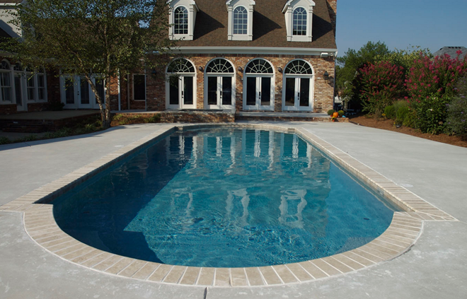 This classically shaped swimming pool has a concrete deck with brick coping and a black interior finish.