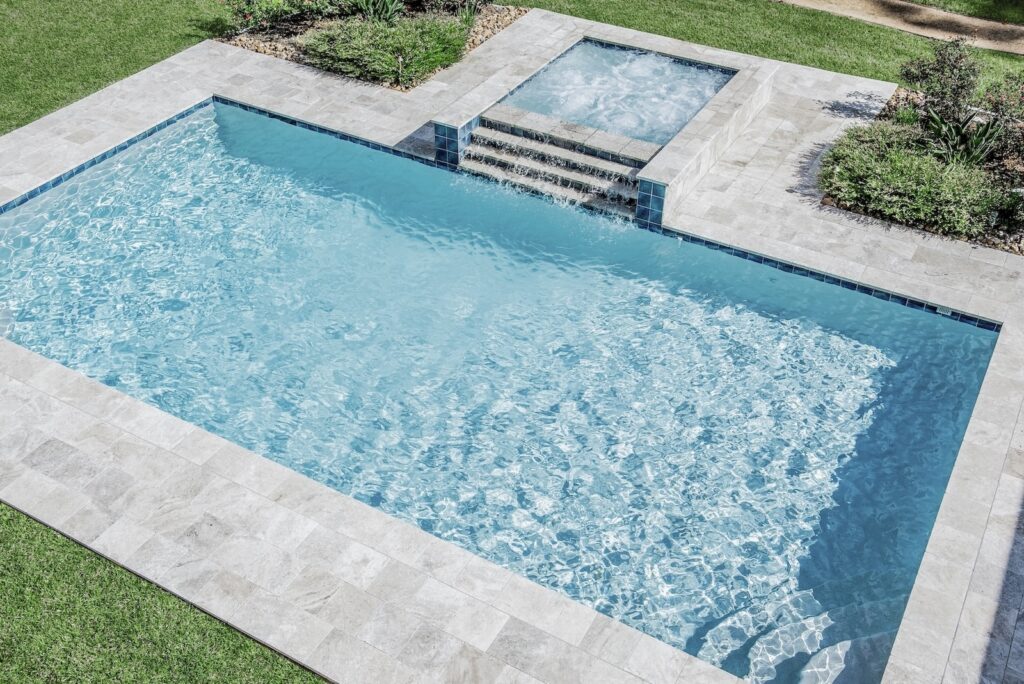 Rectangular pool with spa and stone tile surround